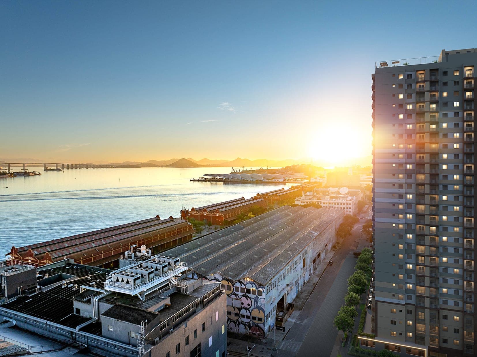 Vista aérea da fachada do edifício residencial ao pôr do sol, com vista para a baía.